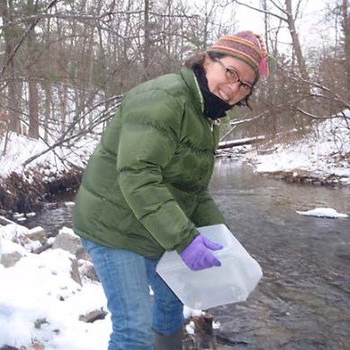 Deb Dial collecting water from a stream during winter